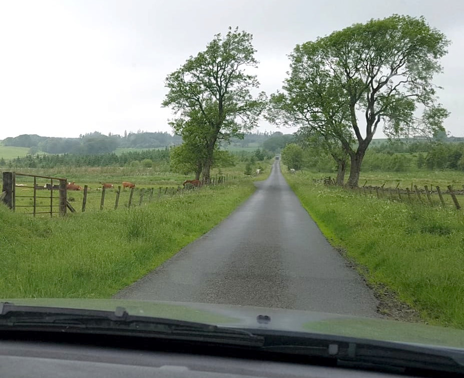 Photo showing view from within a vehicle being driven along the straight road towards North Cloich Woodland.